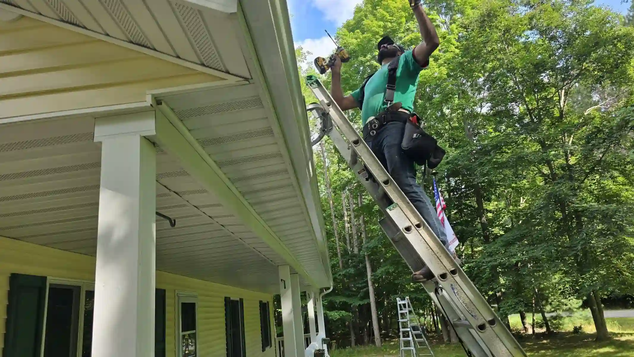 Leading Edge Gutters crew member on a ladder installing a white gutter along a porch roof