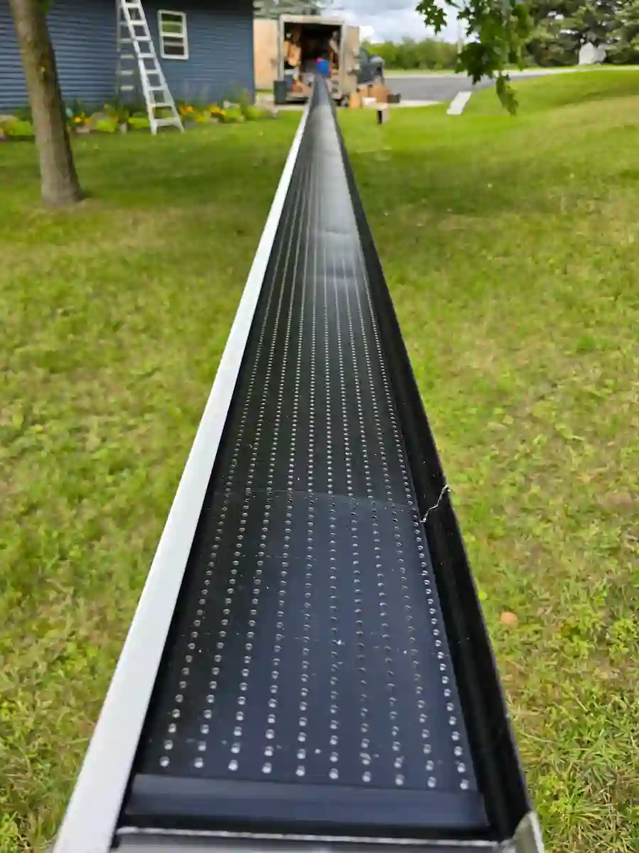 Perforated black gutter guard installed along a gutter