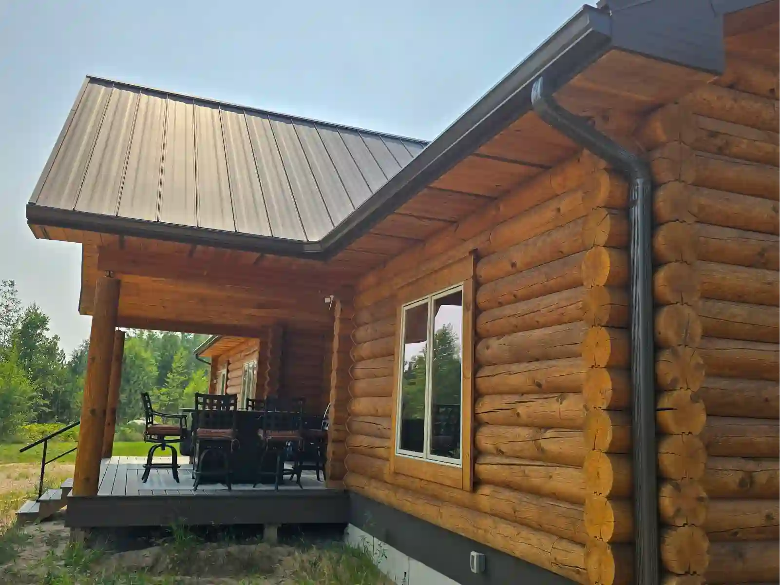 Log home with dark seamless gutters under a standing-seam metal roof